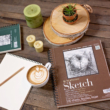 Kép 6/7 - Strathmore barna és zöld spirálos skicctömb fektetve az asztalon grafika rajzzal, kávéscsészével, ceruzával